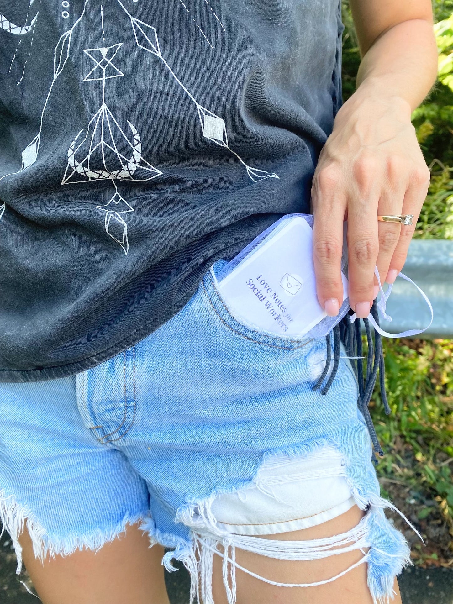 Women pulling card deck out of her jeans pocket to show the cover of the deck "Love Notes for Social Workers".