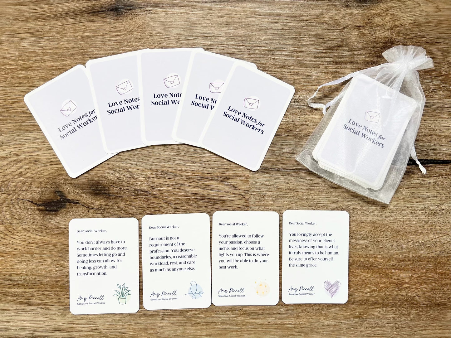 The card deck is displayed so that you can see the back of 5 of the cards which are purple and say "Love Notes for Social Workers" on them. 4 cards are laid out so you can see the front of the cards. They include messages such as "Dear Social Worker, You don't always have to work harder and do more. Sometimes letting go and doing less can allow for healing, growth, and transformation". The rest of the deck in shown inside a white organza bag.
