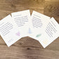 4 prints are fanned out on a wooden surface. Each print is white with dark purple font. Each print has a colorful sketch in the bottom right corner. The top card reads "Dear Social Worker, You lovingly accept the messiness of your clients' lives knowing that is what it truly means to be human. Be sure to offer yourself the same grace. Amy Pinnell, Sensitive Social Worker". The sketch in the bottom corner is a purple heart. 
